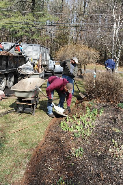 people digging an edge with shovels to a garden planting bed