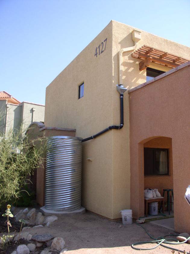 Rainwater storage tank outside adobe house